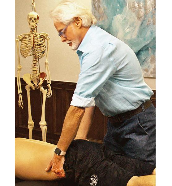 Image 6. Iliosacral Alignment Technique: The therapist's left hand lifts the client's left anteriorly/inferiorly rotated ilium and his right palm braces the right posterior superior iliac spine. The therapist gently pulls with his left hand while resisting with his right. The client is asked to gently push his left ilium towad the table to a count of five and relax. The therapist rotates the client's pelvis to the next restrictive barrier to restore Z-joint alignment.