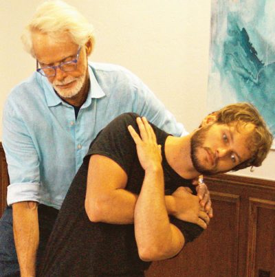Image 5. Passive Sidebending Technique: With his right hand bracing the client's thigh, the therapist's left hand sidebends the client's lumbar spine to stretch the quadratus lumborum and decompress the Z-joints on the client's right side. The client is asked to gently right sidebend against the therapist's resistance to a count of five and relax, and the therapist again left sidebends the client to the next restrictive barrier. Repeat 3-5 times and retest using the Kemp's test.